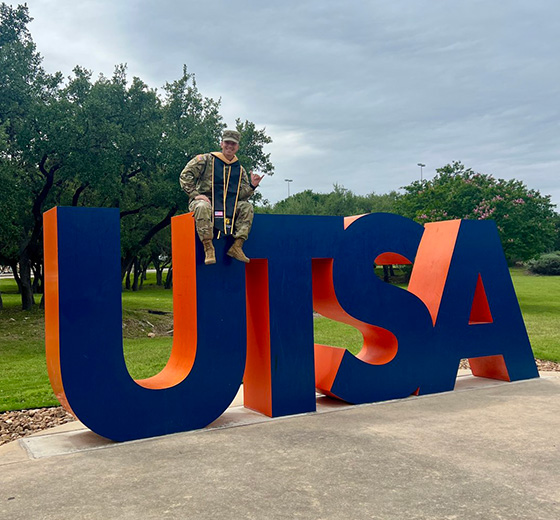 Carlos Camacho sits on top of the UTSA sign