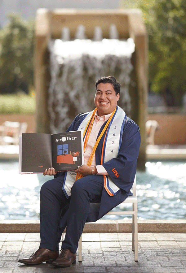 Jacob Salas sitting in front of the Sombrilla Water Fountain