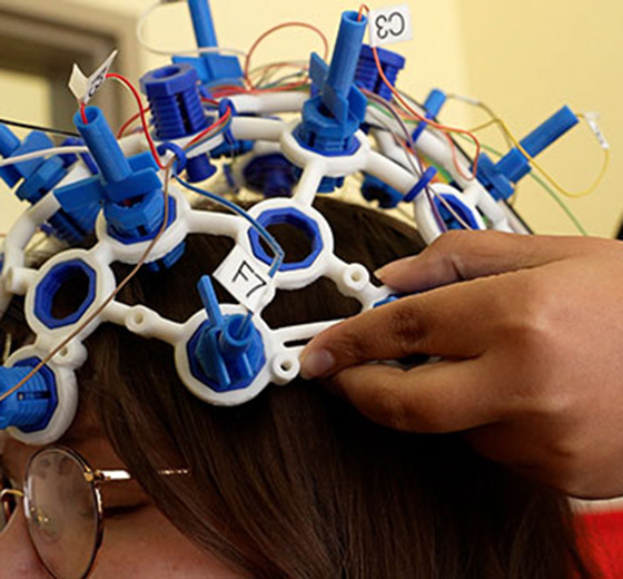 Student places a neurofeedback dry cap onto a patient.