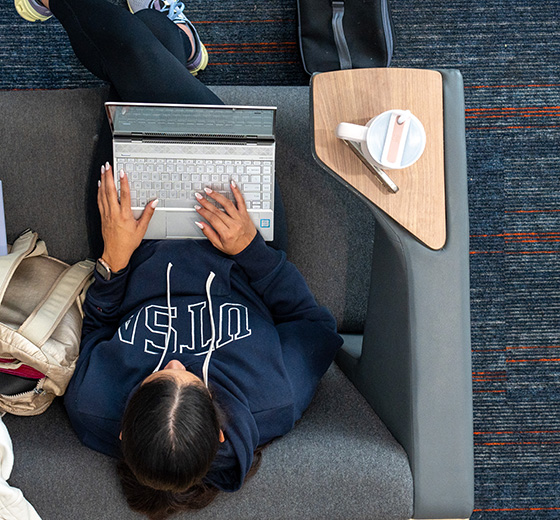 A student works on a laptop in the library