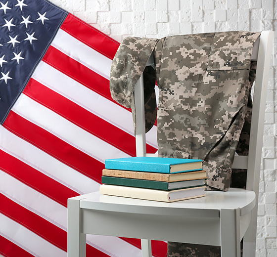 Military uniform draped on a chair with textbooks and an American flag in the background