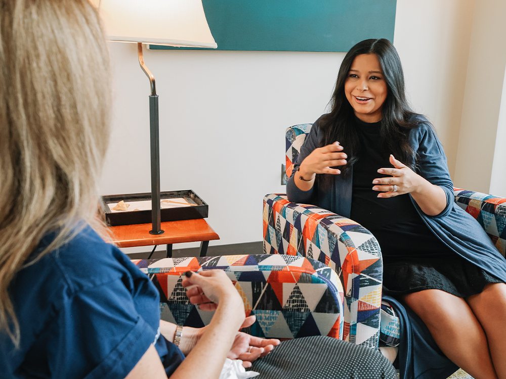 A therapist speaks with a patient in a room.