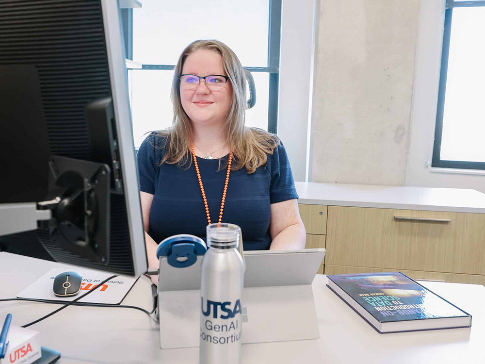 Employee sits at desk looking at computer screen