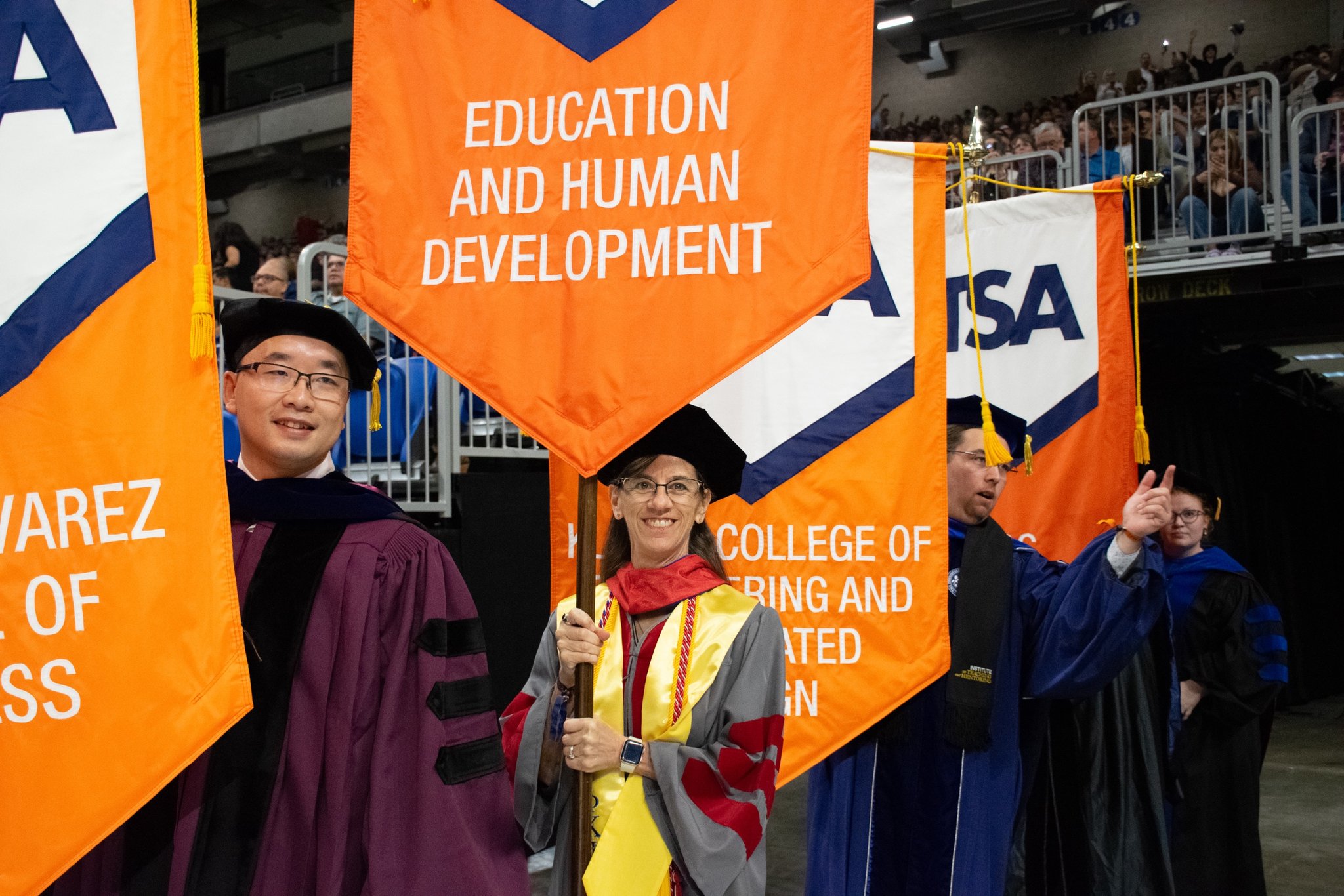 Student holding COEHD banner at commencement